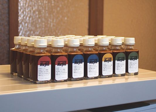レッド・ブルー・イエロー・グリーンのラベルを貼った Espresso Refill の瓶が、白い棚の上に何列も並んでいる