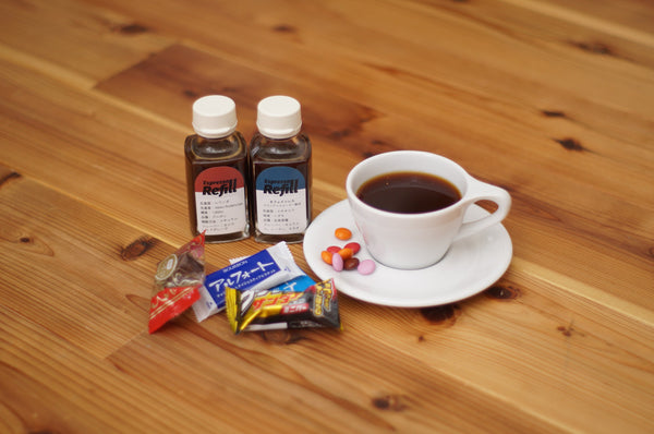 生エスプレッソのレッドとブルー、コーヒーの入ったカップ、ソーサーの粒チョコと市販のチョコレート菓子